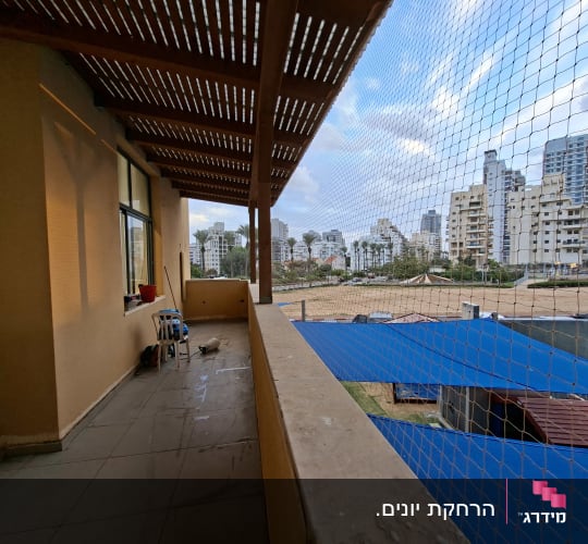 רשת יונים מותקנת על מרפסת עם נוף לעיר